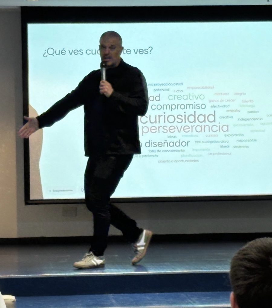 Dani Elhelou en el escenario frente a una pantalla con valores como curiosidad, compromiso y perseverancia
