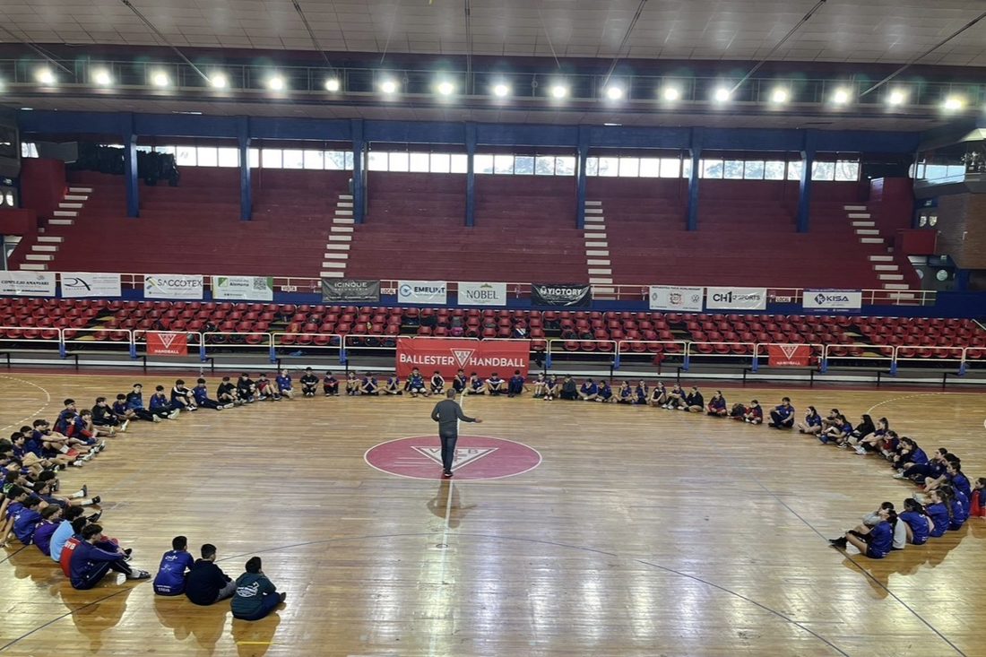 Charla con deportistas sentados en ronda en el estadio de la Sociedad Alemana de Gimnasia